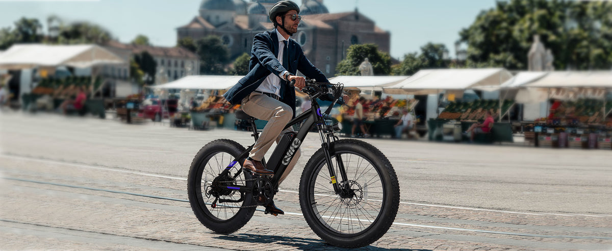 Rider using a black Qlife fat tire electric bike in a town square